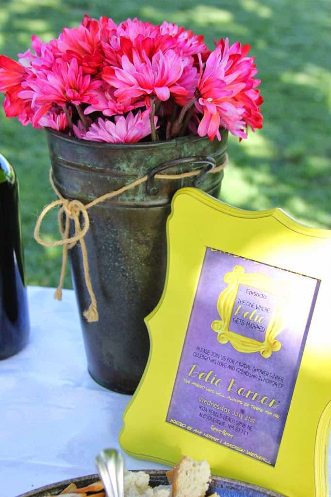 A friends themed bridal shower table with flowers and a bottle of wine.