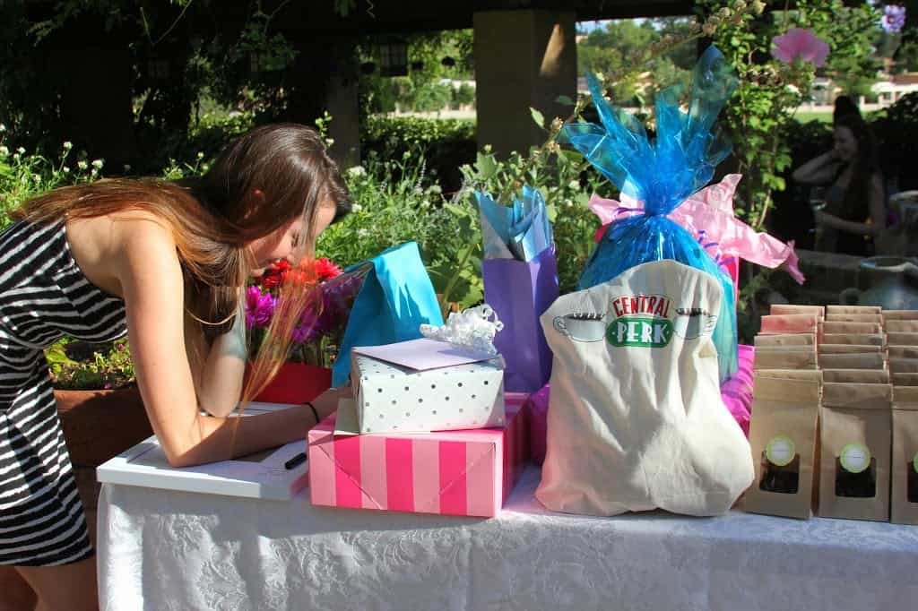 A woman at a friends themed bridal shower looking at a table full of gift bags.