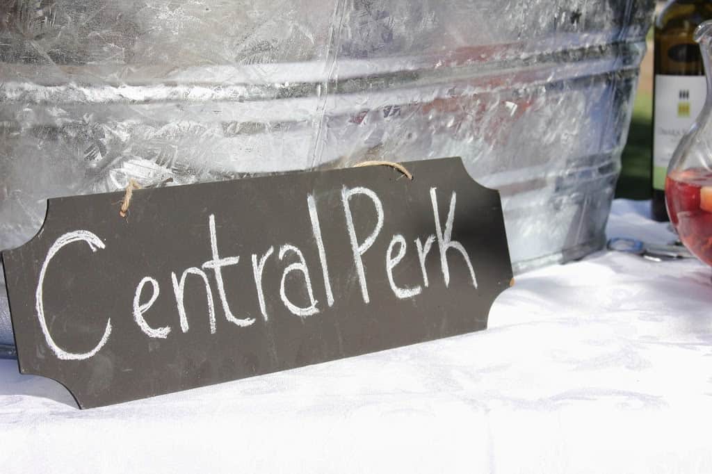 At a friends themed bridal shower, a sign for Central Park sits on a table adorned with a bucket of wine.