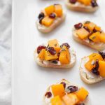 Looking for a perfect fall appetizer? Cranberry Goat Cheese and Butternut Squash Toast is perfect for fall parties, pre-holiday dinner snacks, or just as an appetizer before dinner. This butternut squash toast assembly combines all of the perfect fall flavors, with sweetness from cranberries and butternut squash met with the tanginess and softness of goat cheese spread on a toasted baguette.?