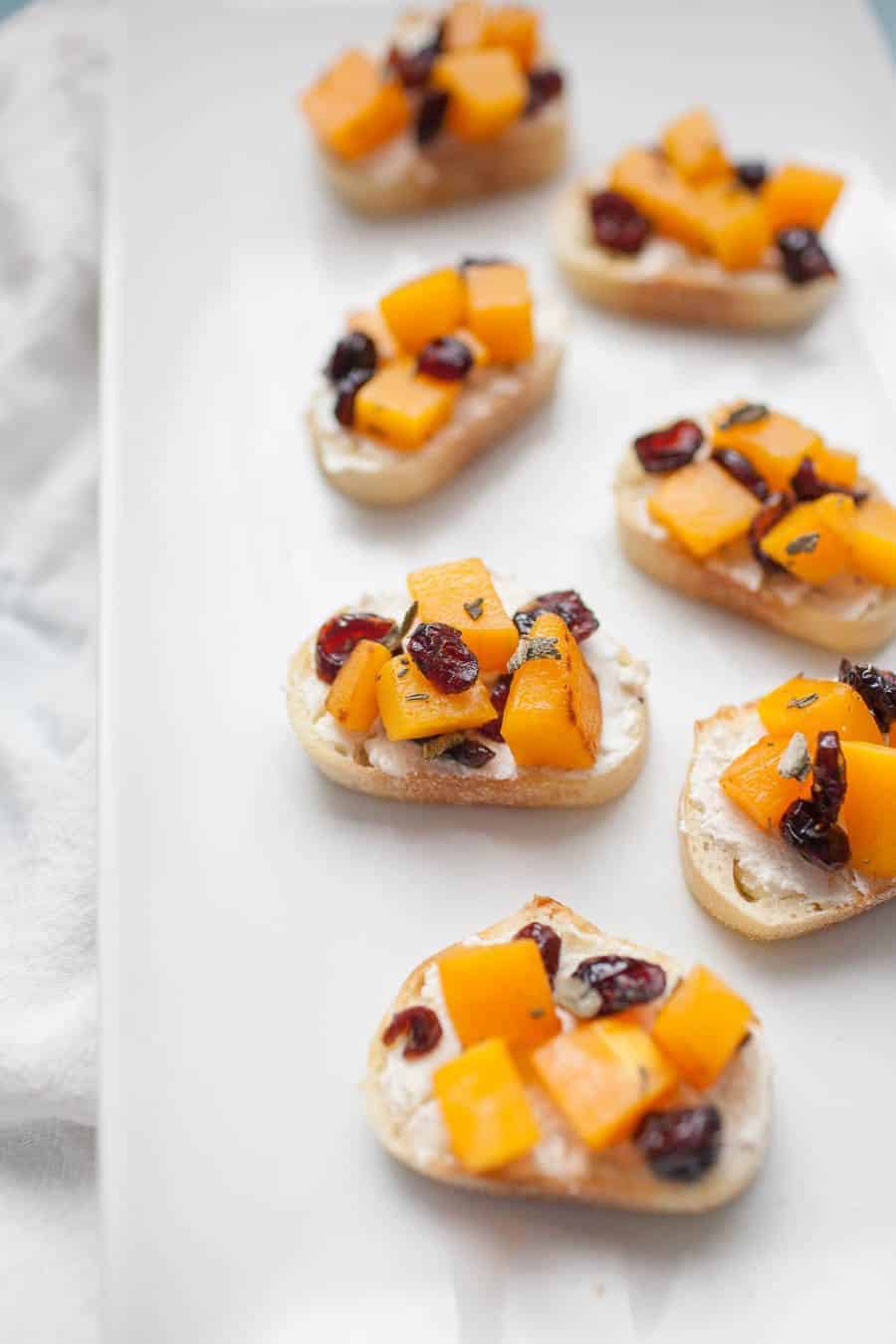 Butternut squash and cranberry crostini on a white plate.