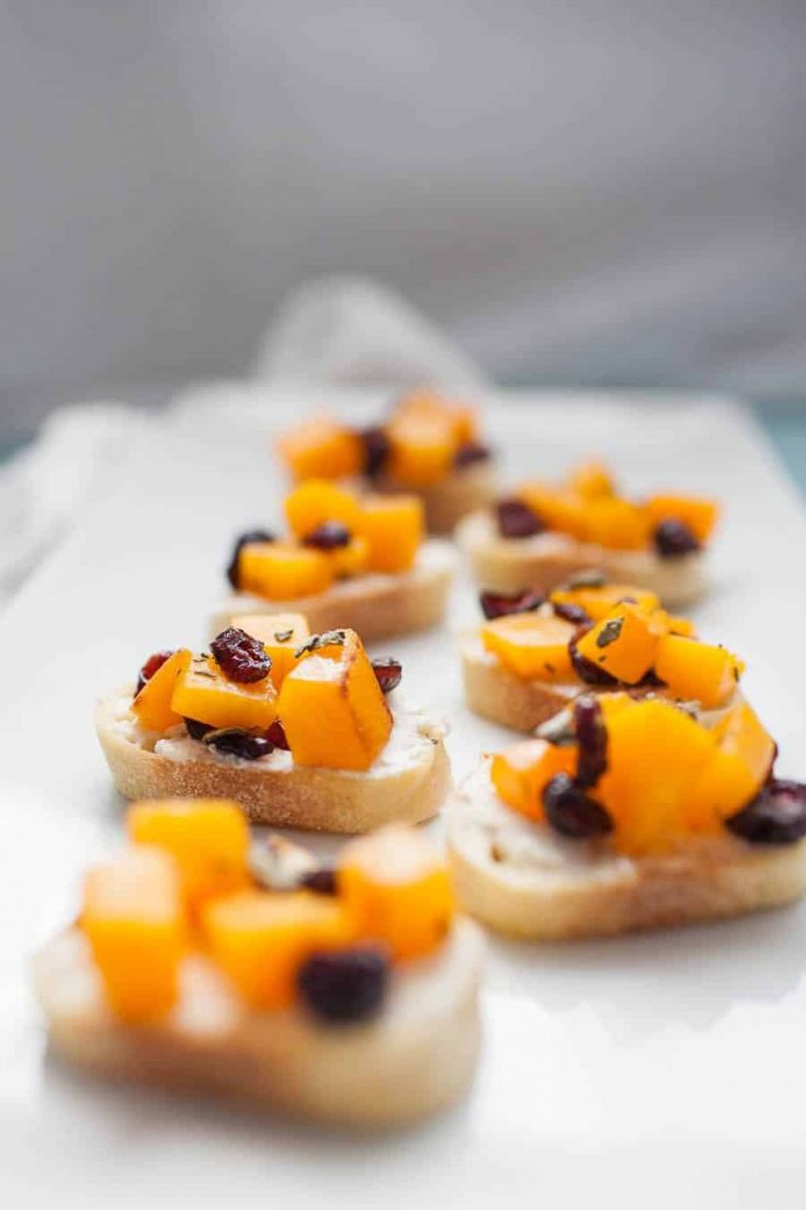 Fall-inspired butternut and cranberry bruschetta on a white plate.