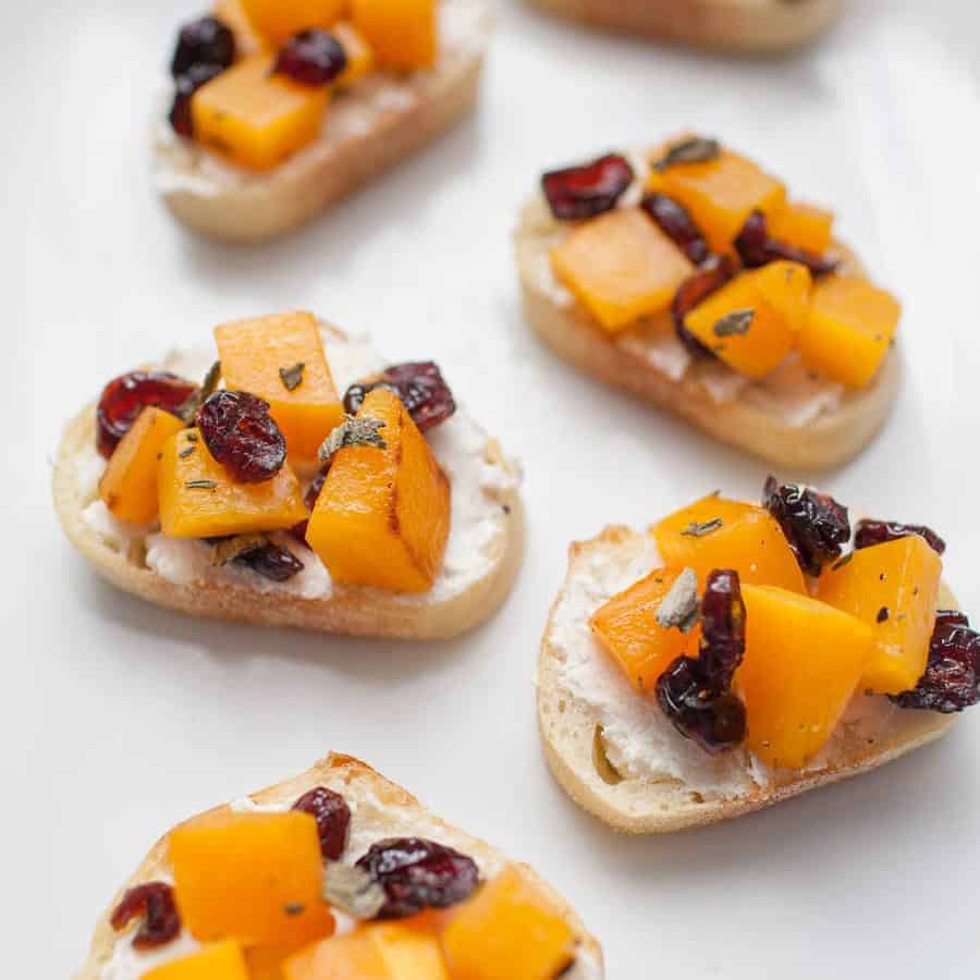 Fall-inspired cranberry and goat cheese bruschetta on a white plate.