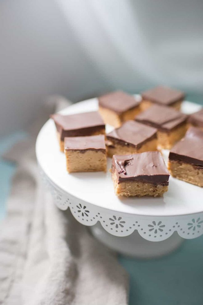 White cake stand with peanut butter and chocolate squares on top.