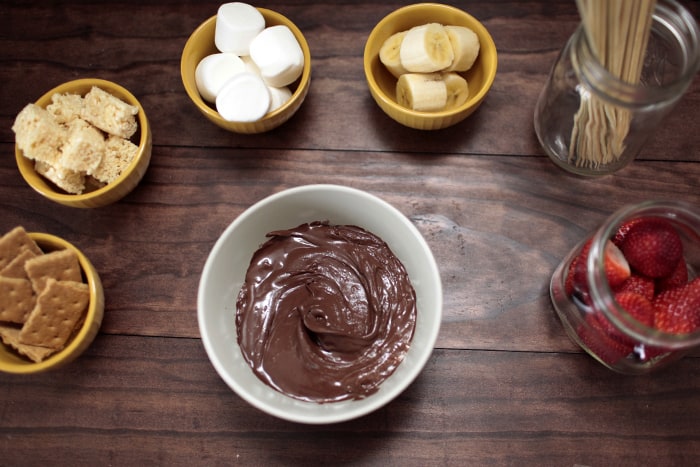 A scrumptious bowl of chocolate dip with strawberries and graham crackers, perfect for a delectable dessert or snack.