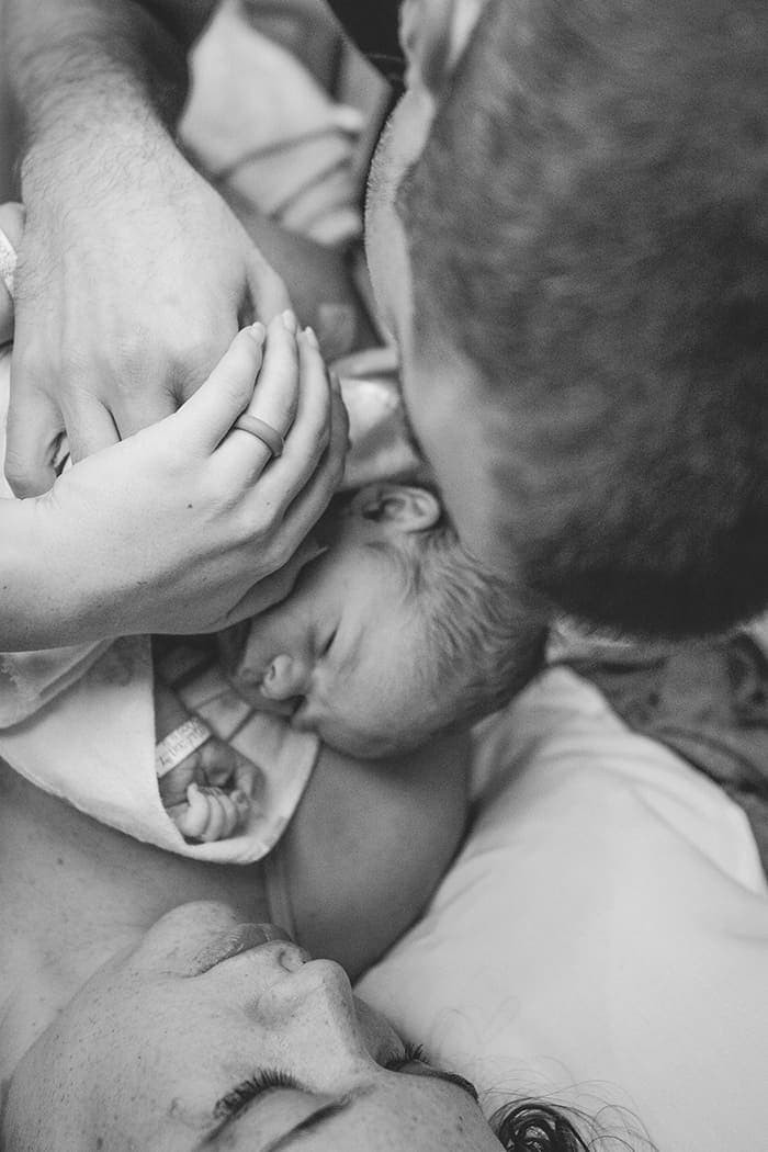 A black and white photo of a man and woman holding a baby.