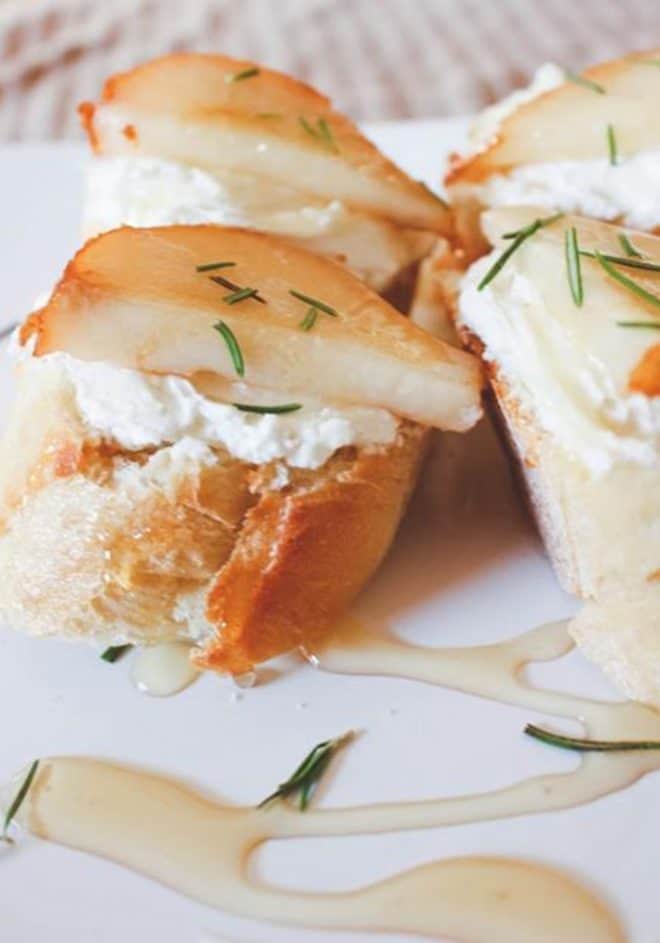 A plate with goat cheese and crostini, topped with pears.