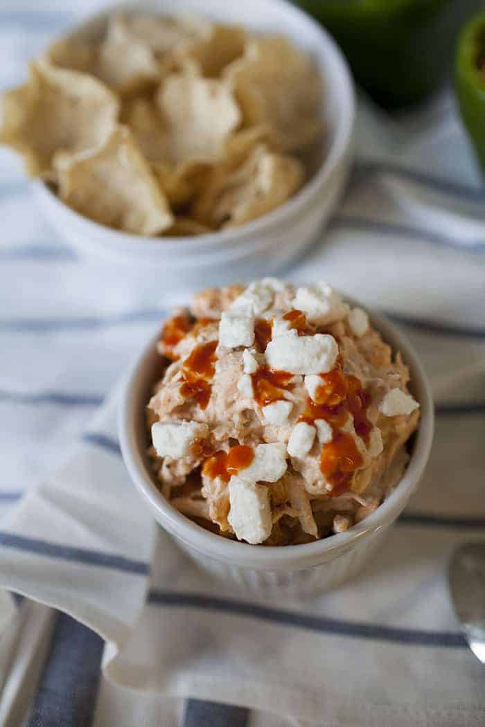 a bowl of tortilla chips next to a bowl of buffalo chicken dip.