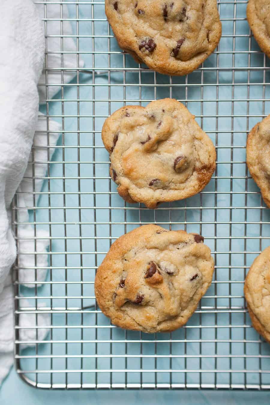 Golden brown, gooey chocolate cookies cooling on a wire rack.