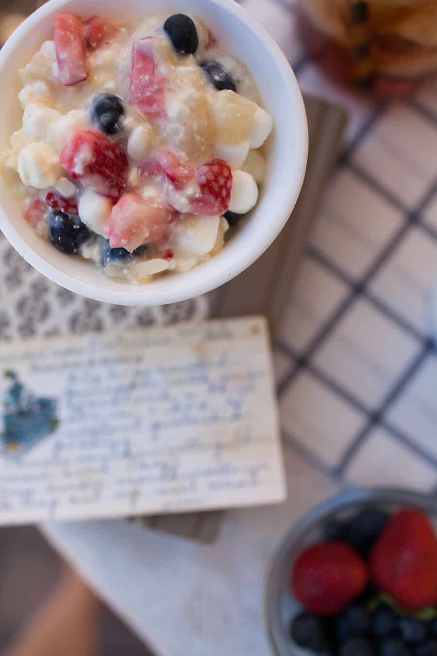A bowl of berries and a note on a table, with red, white, and blue Watergate salad.