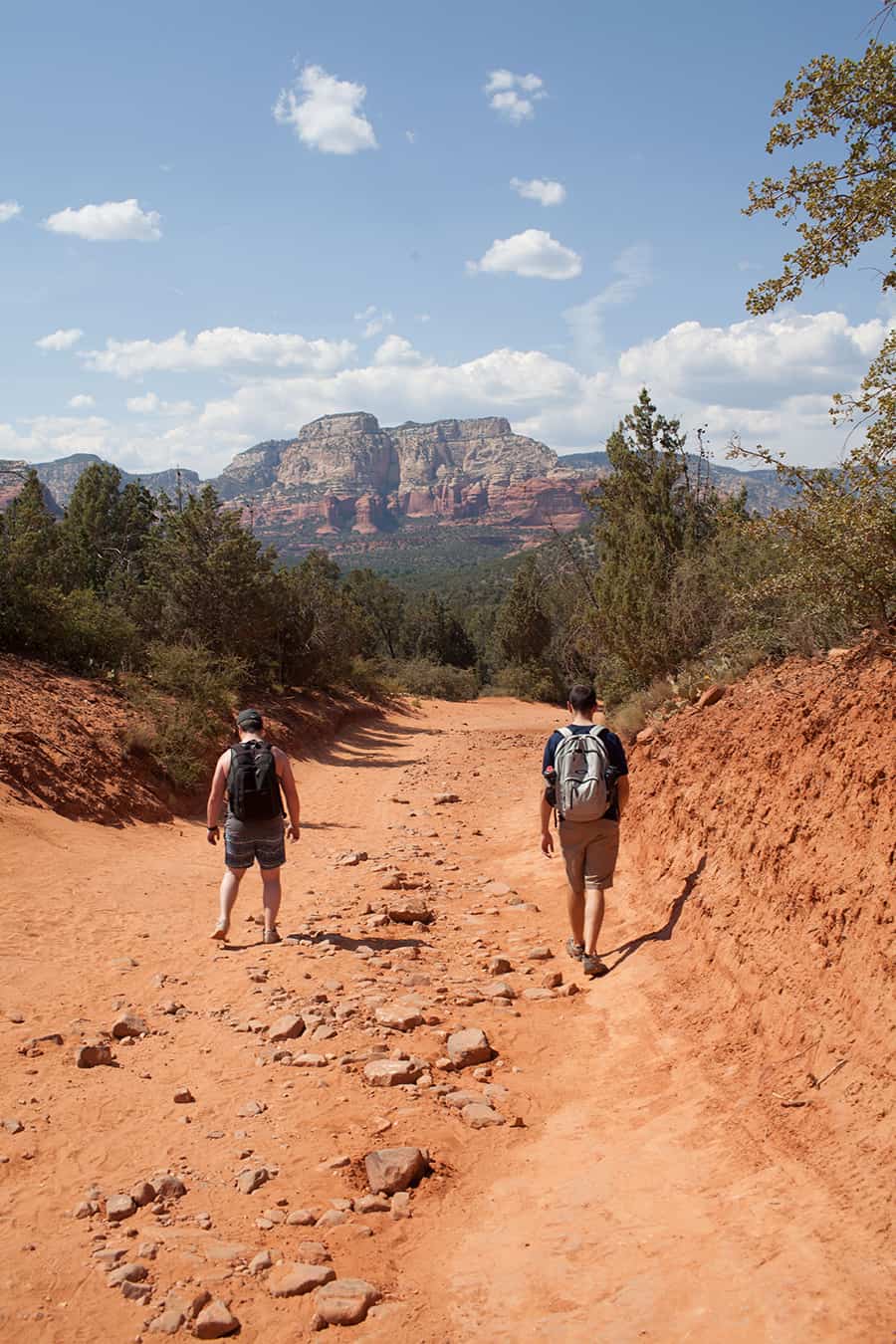 Two men on a phoenix to sedona day trip walking down a dirt trail in Sedona, Arizona.