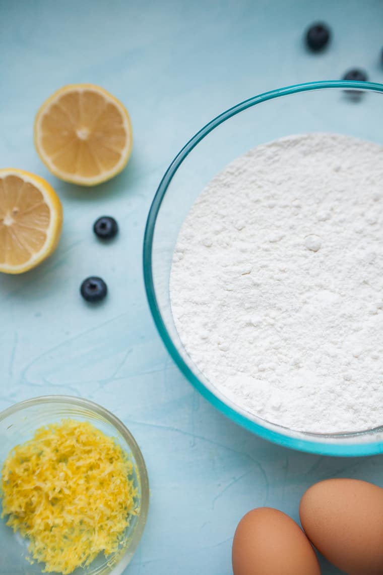 ingredients for lemon blueberry bread on a blue countertop. 