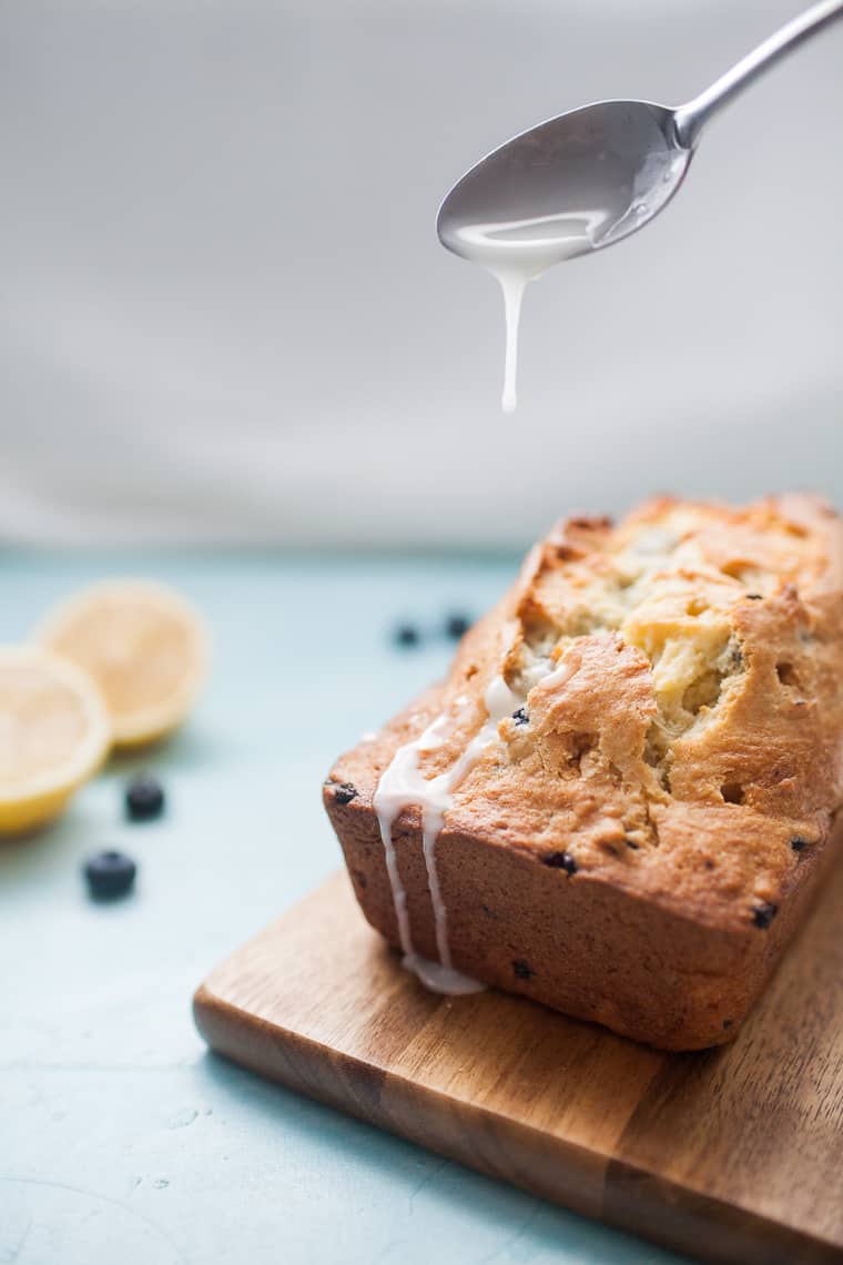 icing dripping onto a loaf of blueberry bread. 