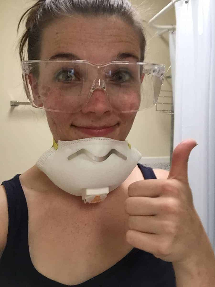 A woman wearing a safety mask in a bathroom.