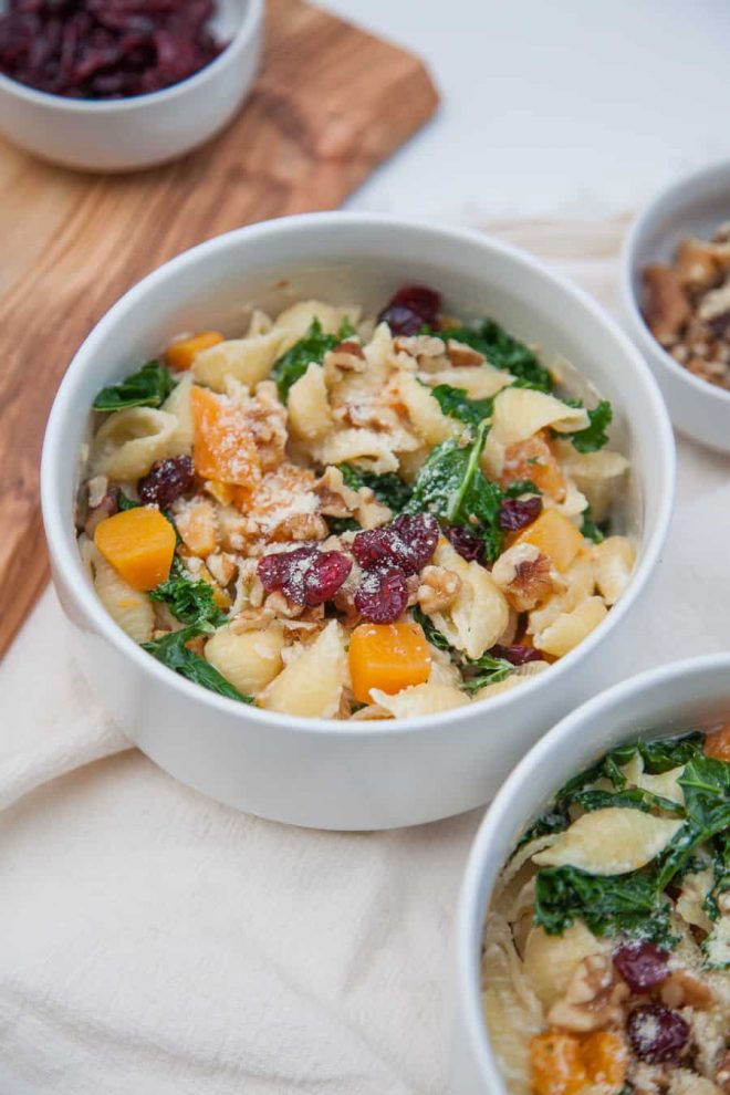 Two bowls of creamy butternut squash kale pasta with cranberries and kale.