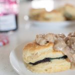 A plate with homemade biscuits and creamy sausage gravy on it.