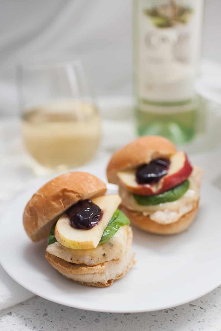 Triple Berry Brie Chicken Sliders on a plate next to a bottle of wine.
