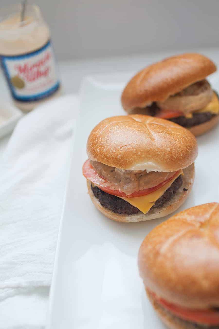 Three miracle whip burgers on a white plate.