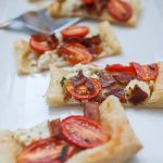 Individual slices of tomato tart on a white rectangular serving plate.