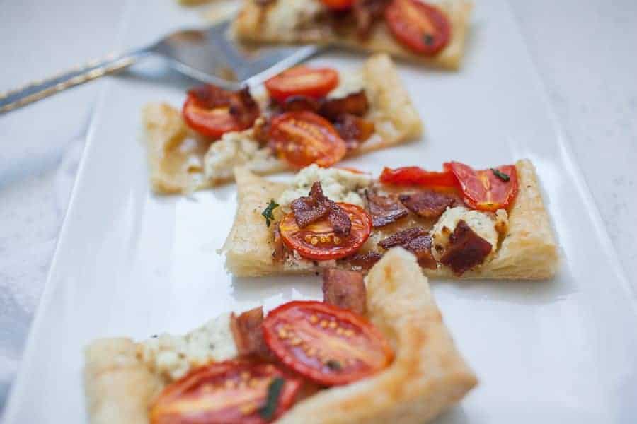 Individual slices of tomato tart on a white rectangular serving plate.