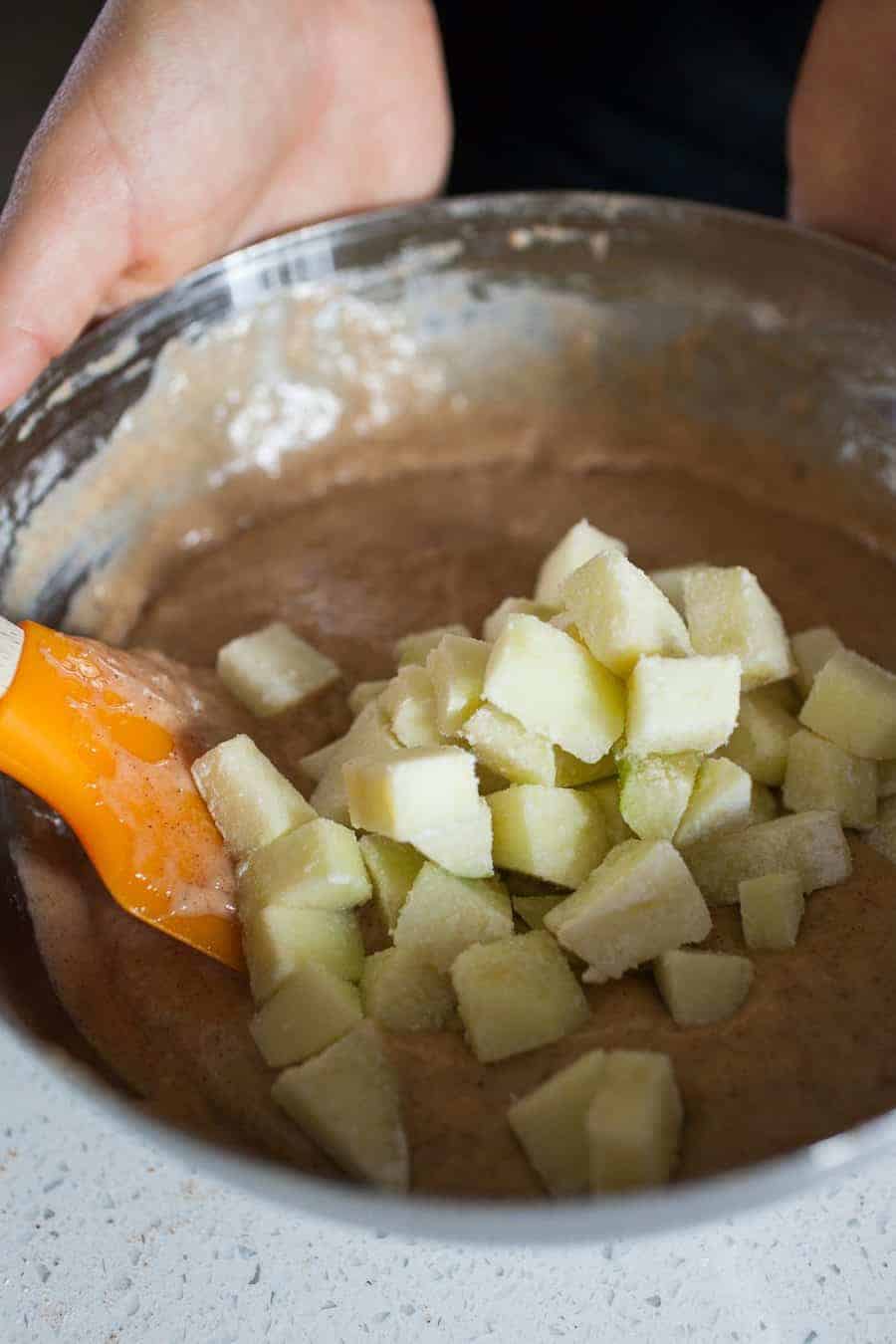 A person is mixing ingredients for Apple Crumble Muffins in a bowl.