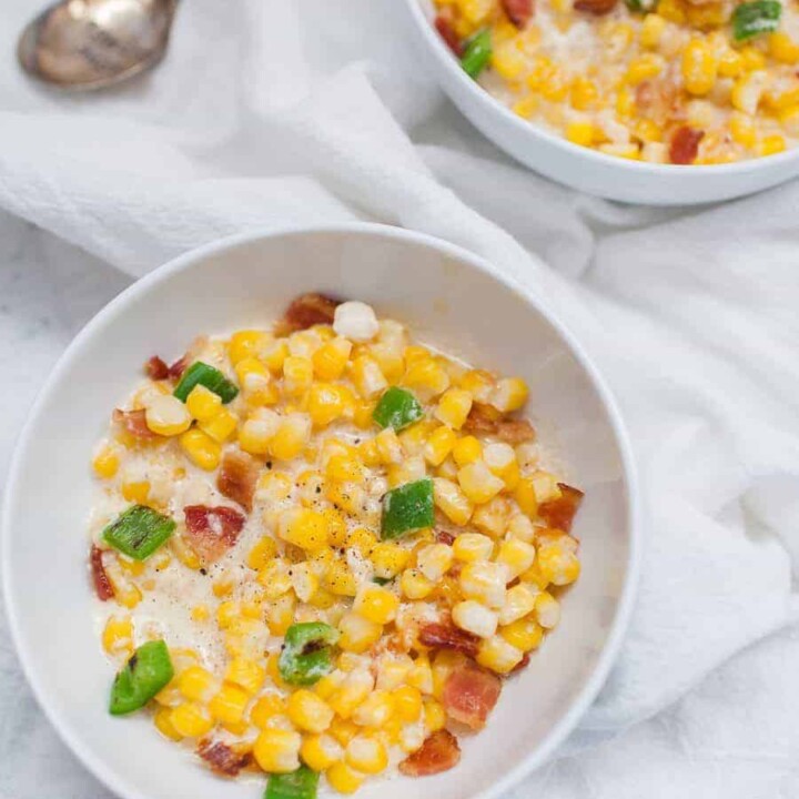 Two bowls of corn on a simple white table.