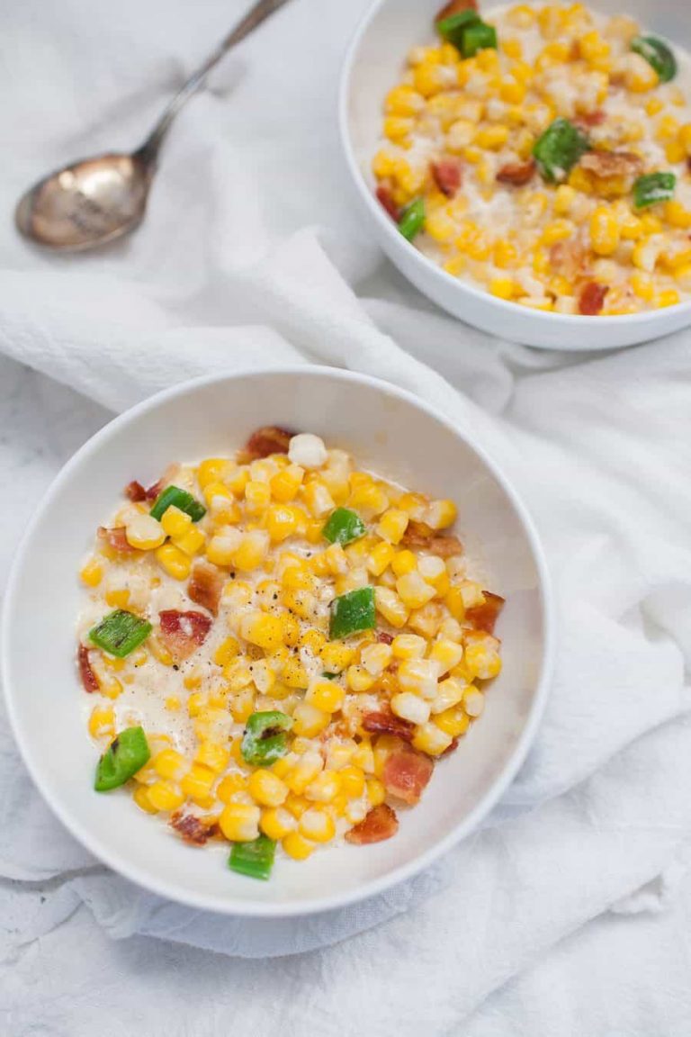 Two bowls of corn on a simple white table.