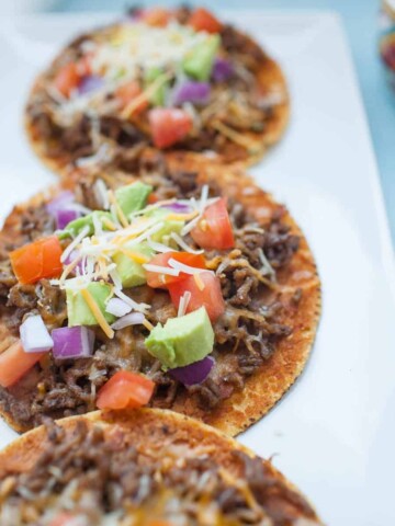 Easy ground beef tostadas are the perfect dinner for busy weeknights! They're quick to make and can be customized a ton of ways to be your perfect flavor combination! Start with a flat, crunchy corn tortilla and add your toppings like beans, ground beef, tomatoes, avocado and cheese for a flavorful, quick dinner.?