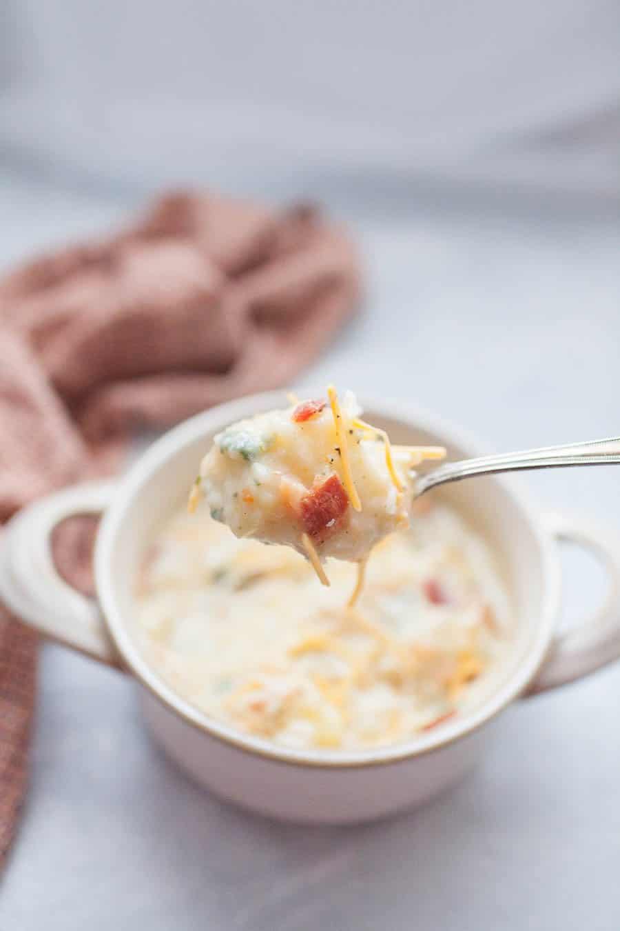 a spoon with a spoonful of baked potato soup. 