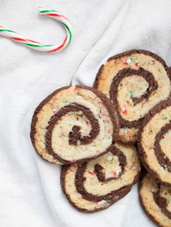 Chocolate Peppermint Pinwheel Cookies are the perfect cookie to share during the holidays! Two sheets of cookie dough, one that is smooth and chocolatey and one that is infused with peppermint and candy cane peppermint pieces, are rolled together to create these beautiful and festive pinwheel cookie slices. If you dream about the combination of peppermint and chocolate together during the holidays, these chocolate peppermint pinwheel cookies will be your new favorite Christmas cookie!