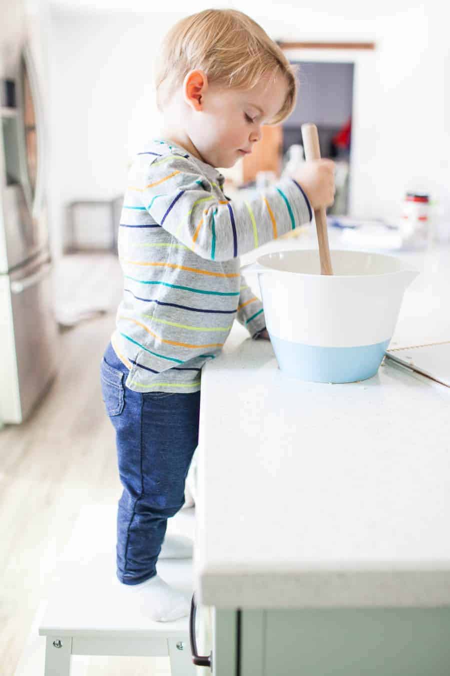 Teaching your toddler to help in the kitchen can be a daunting task, but it's one that can take away the stress of having to keep an eye on your kiddos while trying to prep dinner or a snack. Teaching your little ones about being in the kitchen can be fun and stressless with a few quick tips for cooking with toddlers!