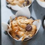 Close up photo of banana chocolate chip muffin in lined muffin pan.