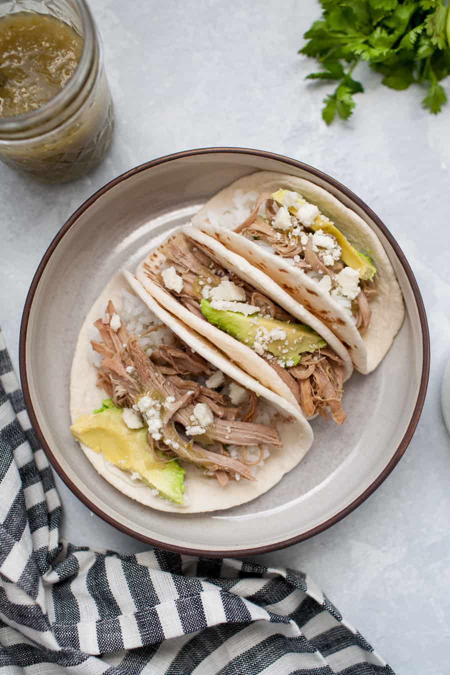 These Salsa Verde Pulled Pork tacos are the perfect dish for lunch, dinner, or just because they're so yummy! They're made with slow cooker Salsa Verde Pulled Pork, cotija cheese, avocado and a little extra salsa verde poured on for good measure. You don't need an occasion to indulge with these tacos!