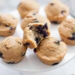 Lemon blueberry muffin with a bite taken out of it on a cake stand.