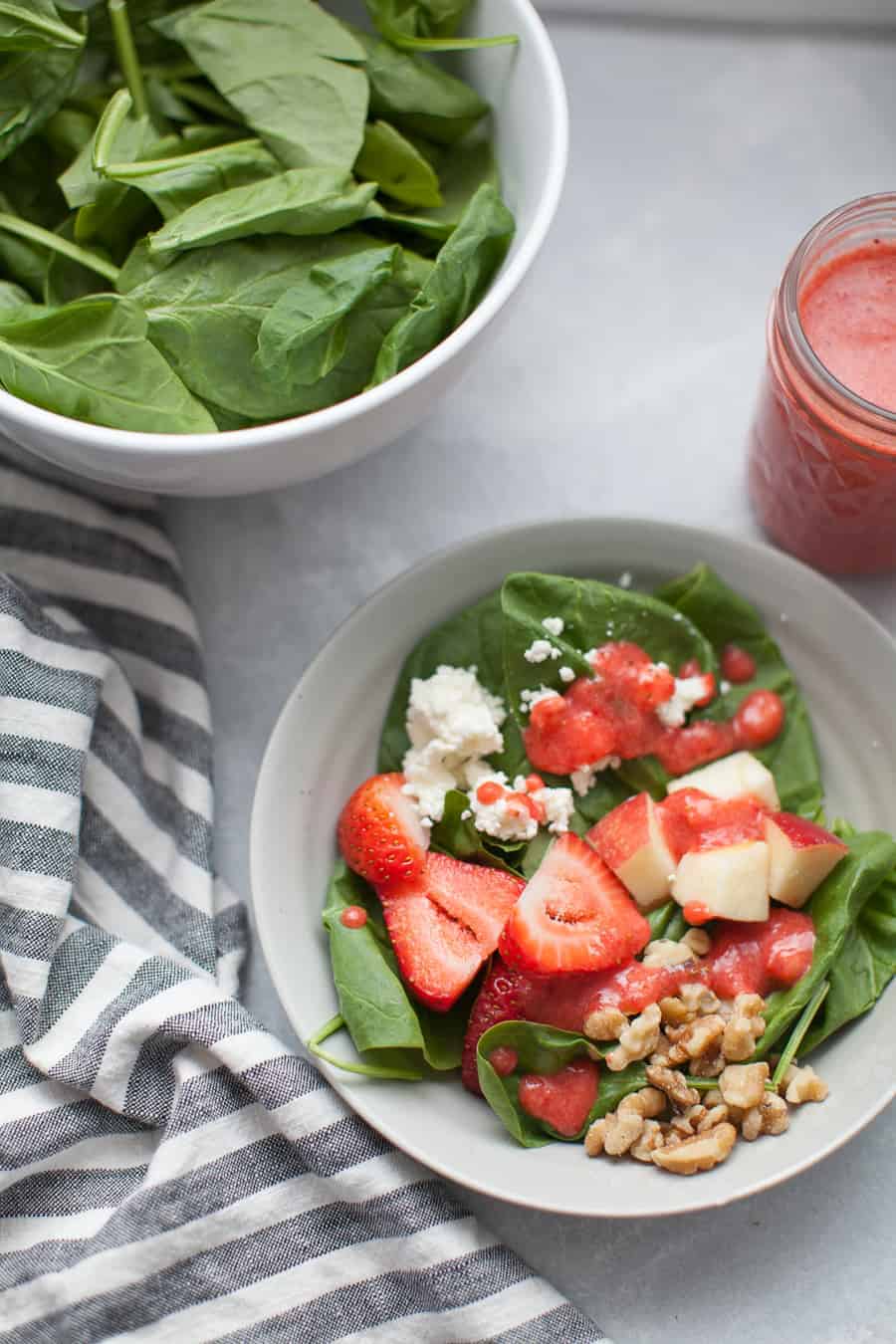 Add this?Strawberry Vinaigrette Spinach Salad to your regular diner rotation! This salad has a spinach base, topped with walnuts, goat cheese, fresh strawberries, diced apples and finally tossed in a homemade strawberry vinaigrette dressing. The dressing is a perfect balance of sweet and tangy. This salad is perfect for any time of year, but especially satisfying for summer and fall!