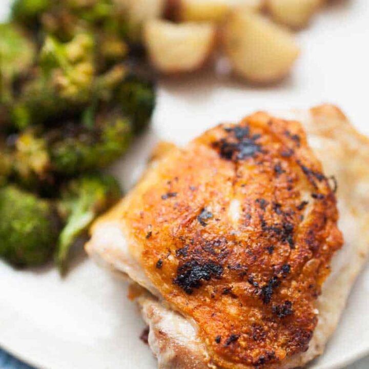 A plate with a succulent piece of lemon pepper chicken thigh, cooked broccoli, and diced potatoes.