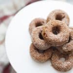 Stack of mini pumpkin donuts on a white cake stand.