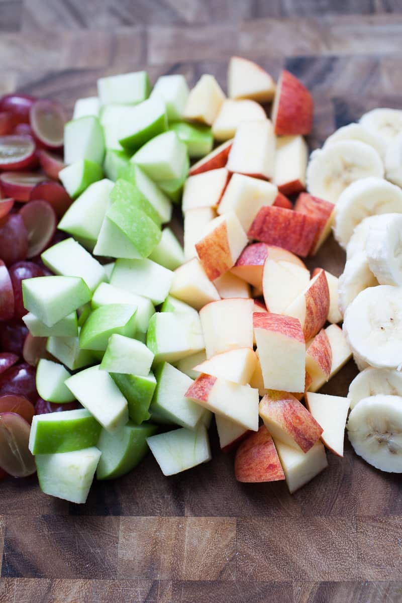 Wooden cutting board with chopped fruit.