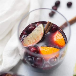 Glass of sangria made with lime, orange and cranberry.