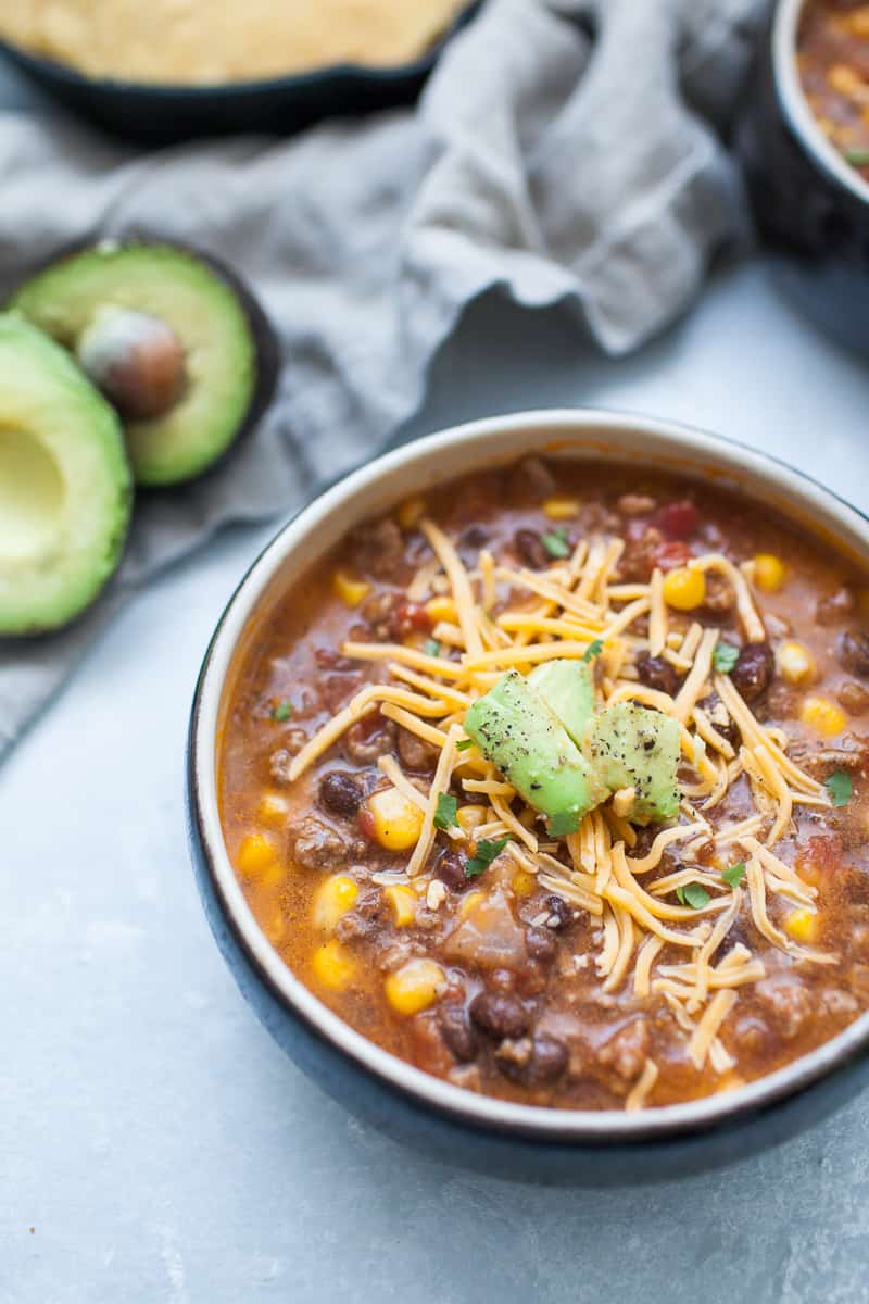 Black soup bowl with taco soup, ground beef, corn, beans, tomatoes, cheese and avocado.