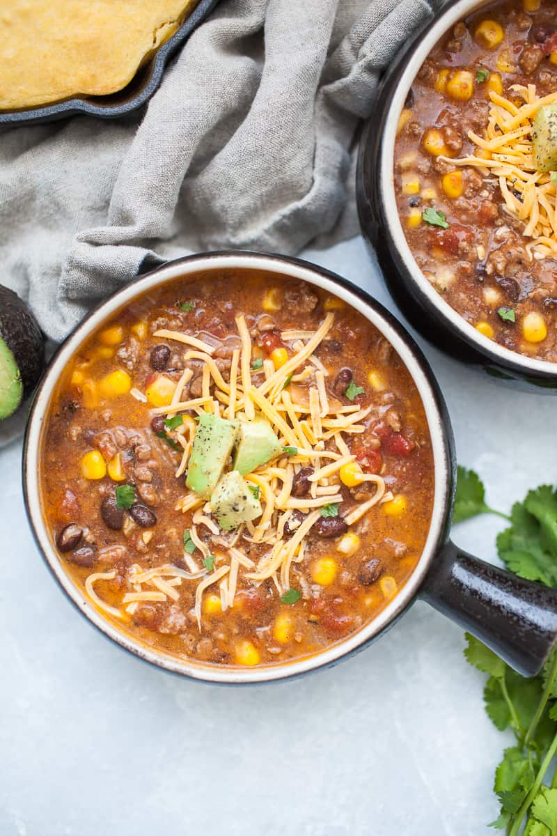 Black soup bowl with taco soup, ground beef, corn, beans, tomatoes, cheese and avocado.