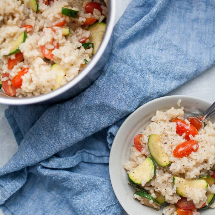 Gray bowl with vegetable risotto on top of a blue linen napkin.