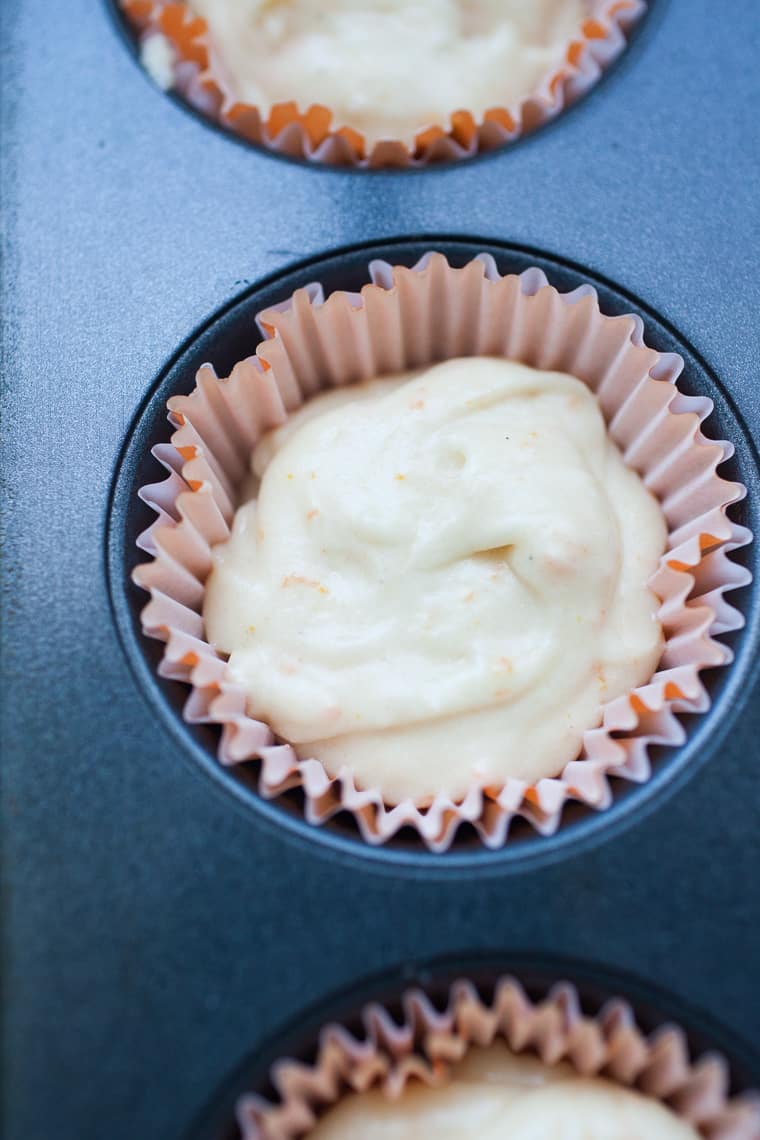 orange cupcake batter in a muffin liner in a muffin tin