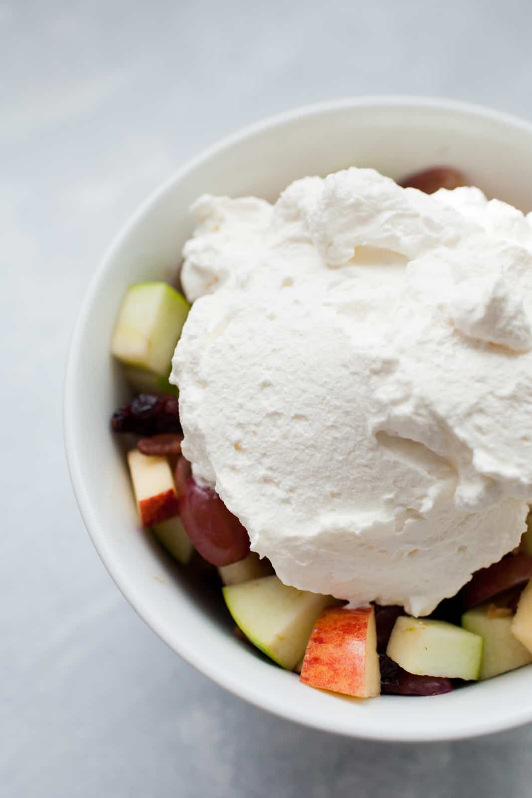 a bowl of fruit salad with a scoop of homemade whipped cream