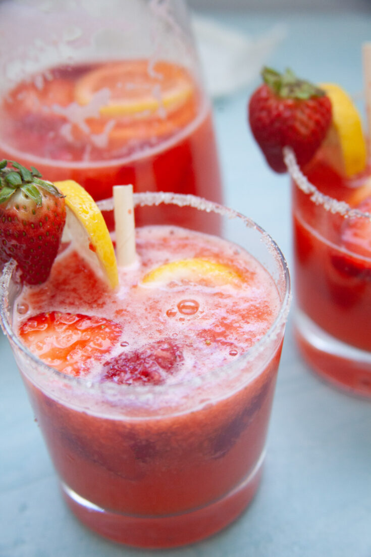 a closeup photo of the strawberry lemonade mocktail with slices of lemon and strawberries for garnish