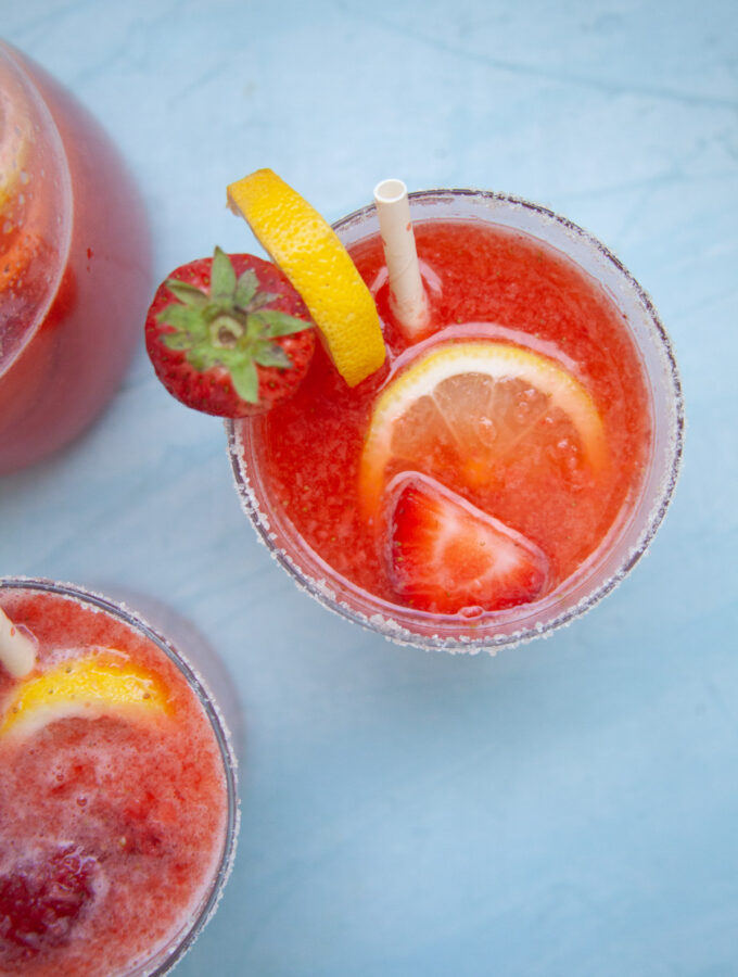 a closeup photo of a red strawberry lemonade mocktail with slices of lemon and strawberries for garnish