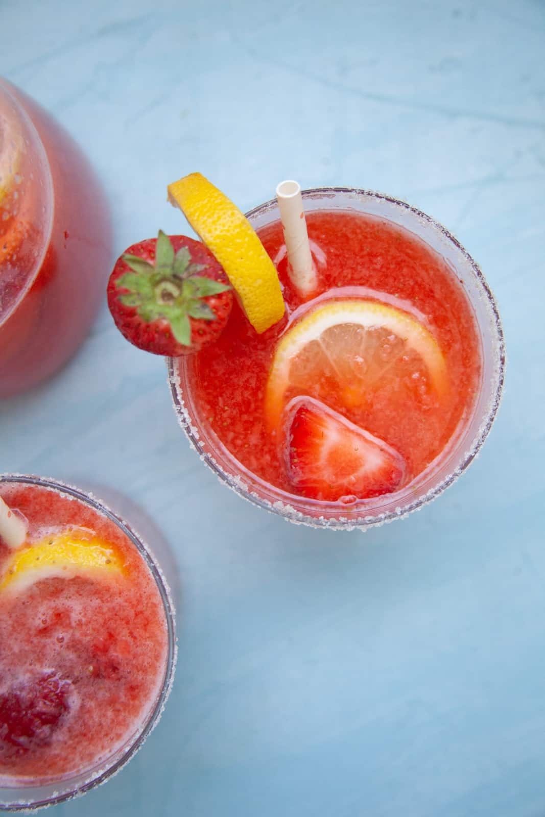 a closeup photo of a red strawberry lemonade mocktail with slices of lemon and strawberries for garnish