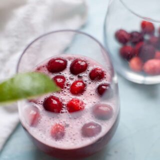 closeup of frozen cranberries in a glass of cranberry ginger ale punch