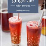 Two tall glasses filled with strawberry ginger ale and sorbet, each garnished with a straw. A person's hand is visible on the right side of the image. Text overlay reads "strawberry ginger ale with sorbet." Perfect for pairing with lemon pepper chicken thighs.