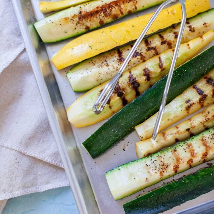 tongs on a tray of zucchini and squash